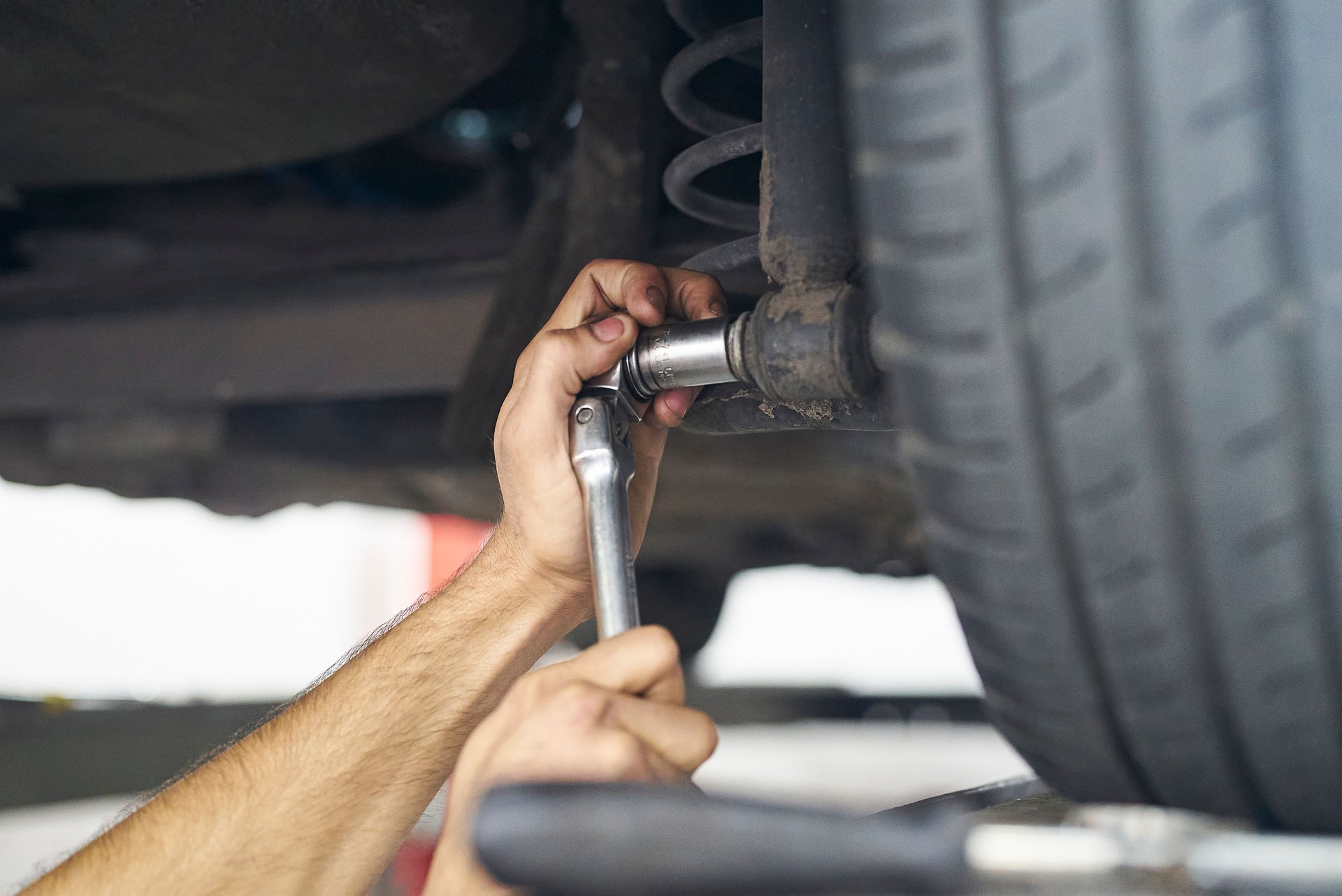 Close-up of male mechanic hands adjusting car suspension